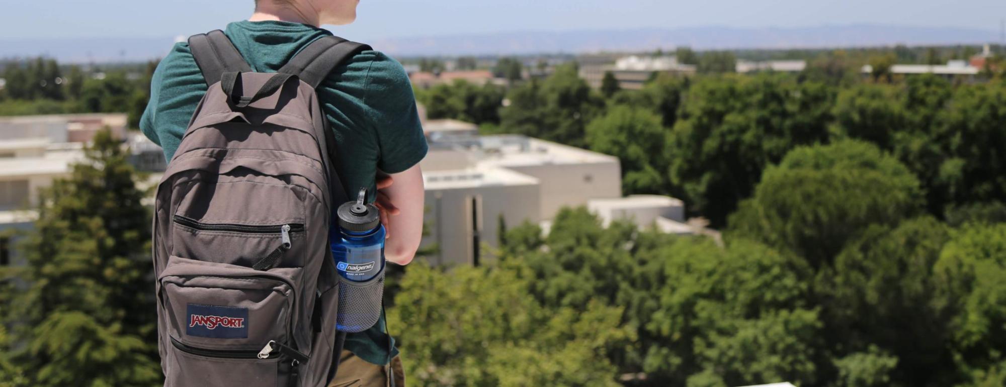 student looking off the horizon of a building roof