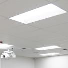 White drop ceiling with recessed lights and two ceiling-mounted projectors, wall clock